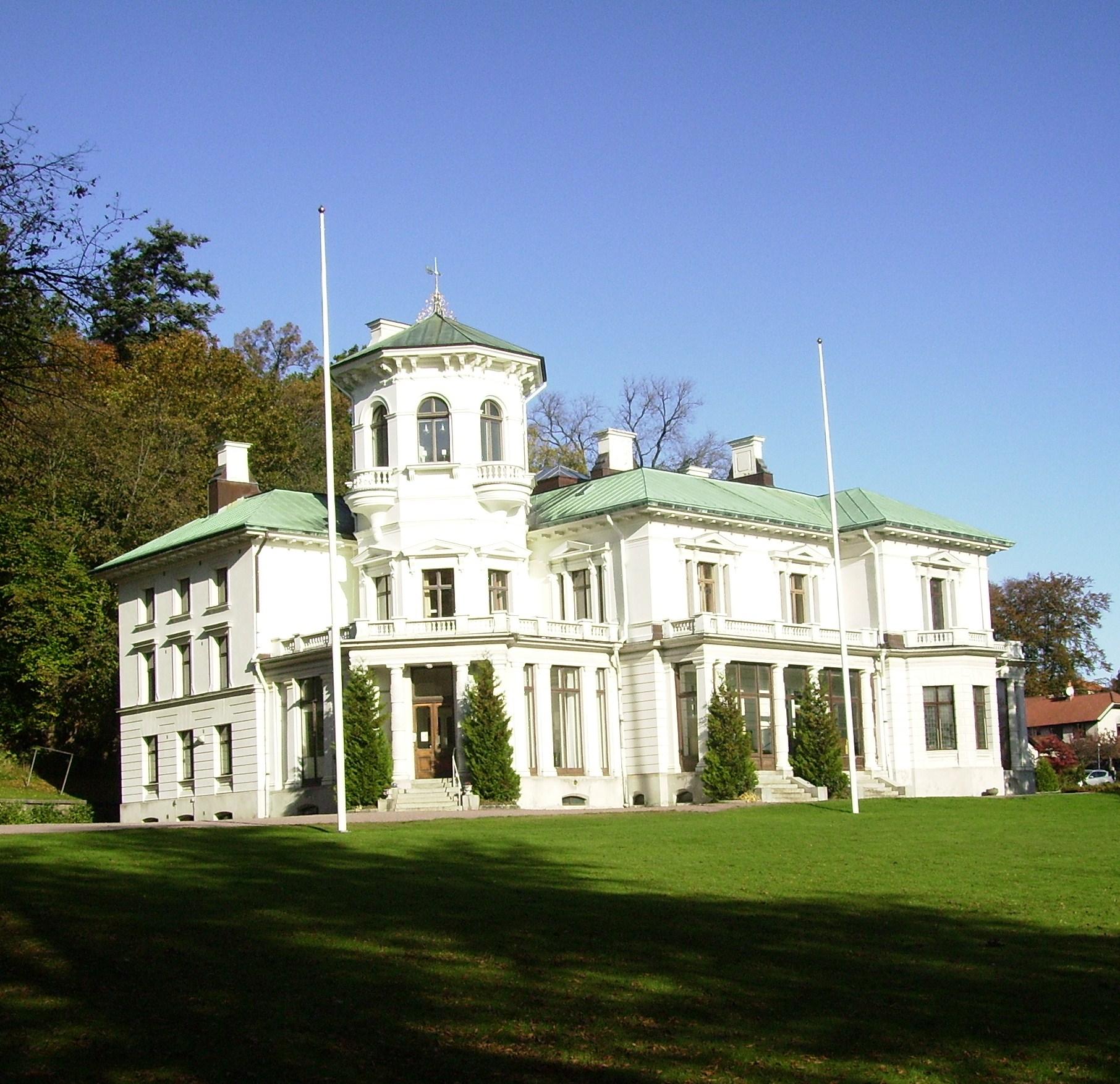 Överås slott, vitt stenhus med torn och grönt tak, sett från gräsmattan